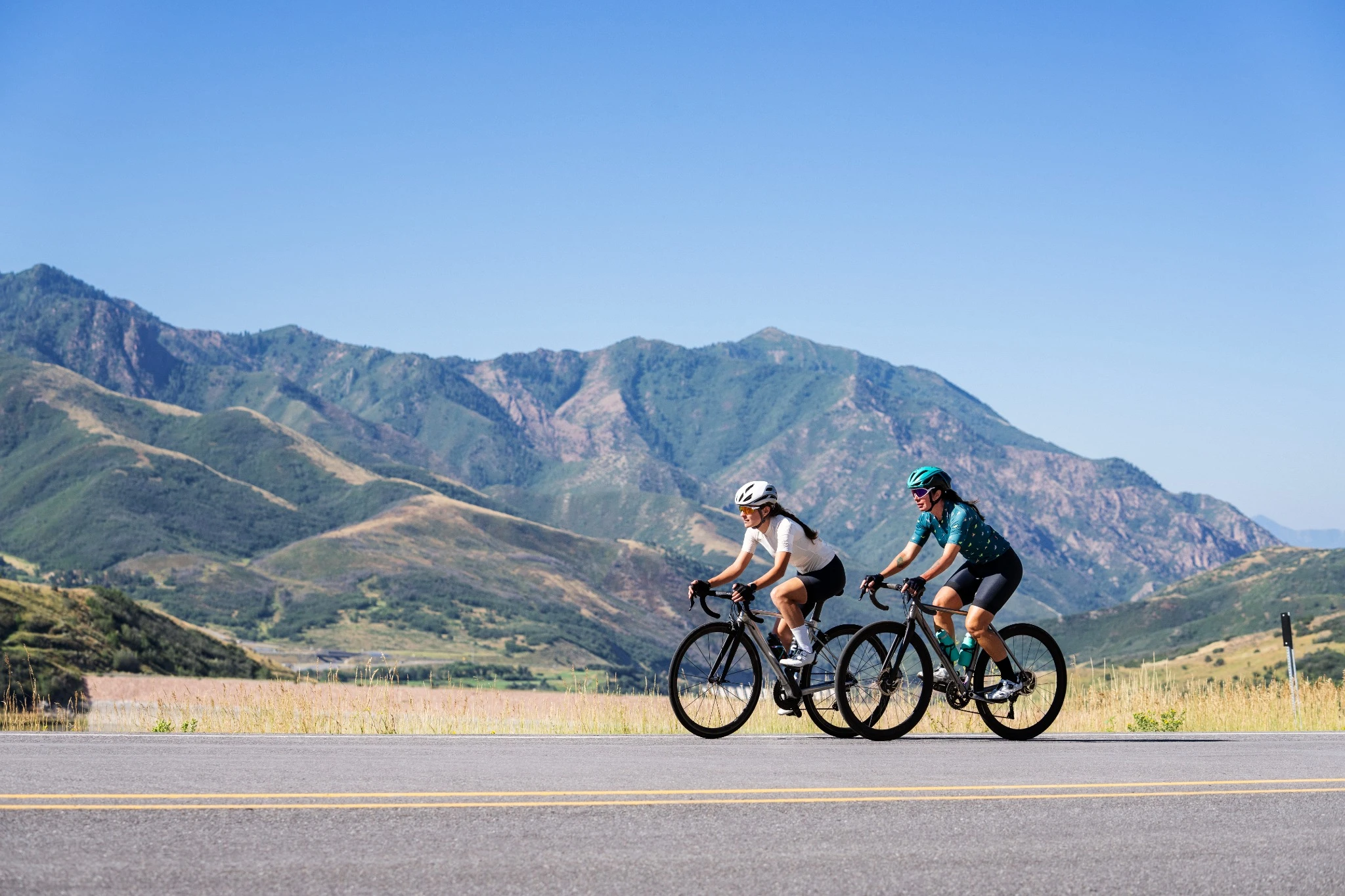 Two cyclists riding road bikes on a mountain road