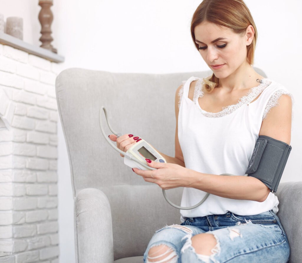 Person seated using upper arm BP monitor with correct cuff placement