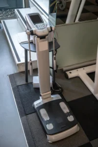 Clinical bioelectrical impedance analyzer machine with hand electrodes and foot pads used for body composition measurement in a fitness or medical setting.