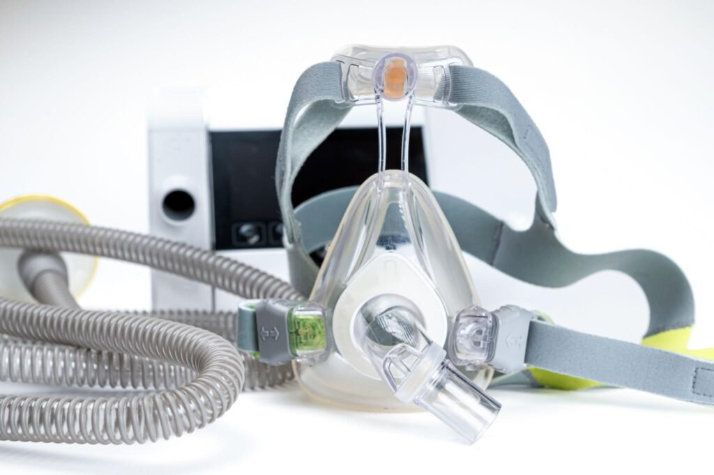 Full-face CPAP mask with headgear and tubing connected to a CPAP device, shown close up.